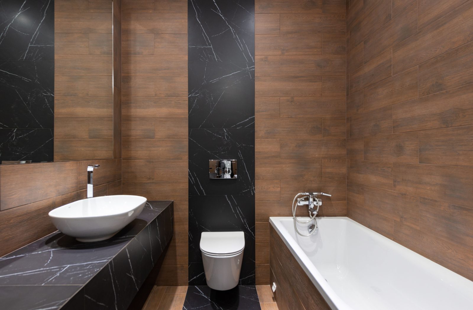 Finished bathroom with vessel sink, wall-hung toilet and wood and marble tile