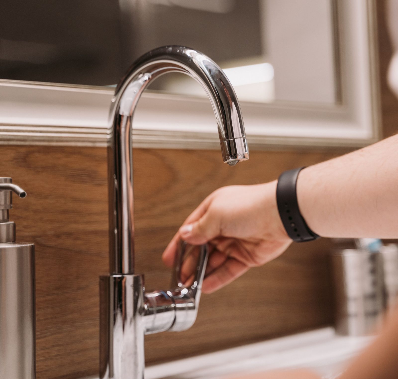 Hand adjusting a chrome gooseneck faucet
